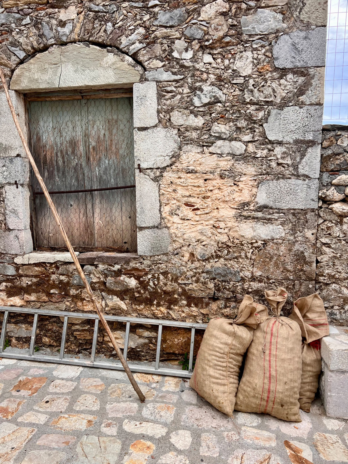 Harvest sacks beside a stone building in Mani